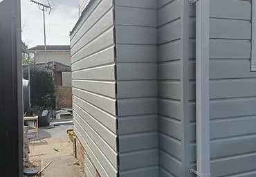 Finished cladding with white guttering and downpipe