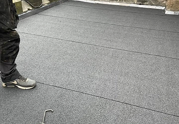 Finished felt flat roof against a stone wall