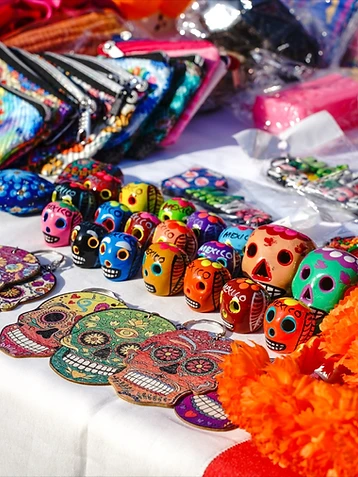 Banco di artigianato messicano con teschi di ceramica dipinti a mano e fiori di cempasúchil, edizione 2024 del Día de los Muertos Roma.