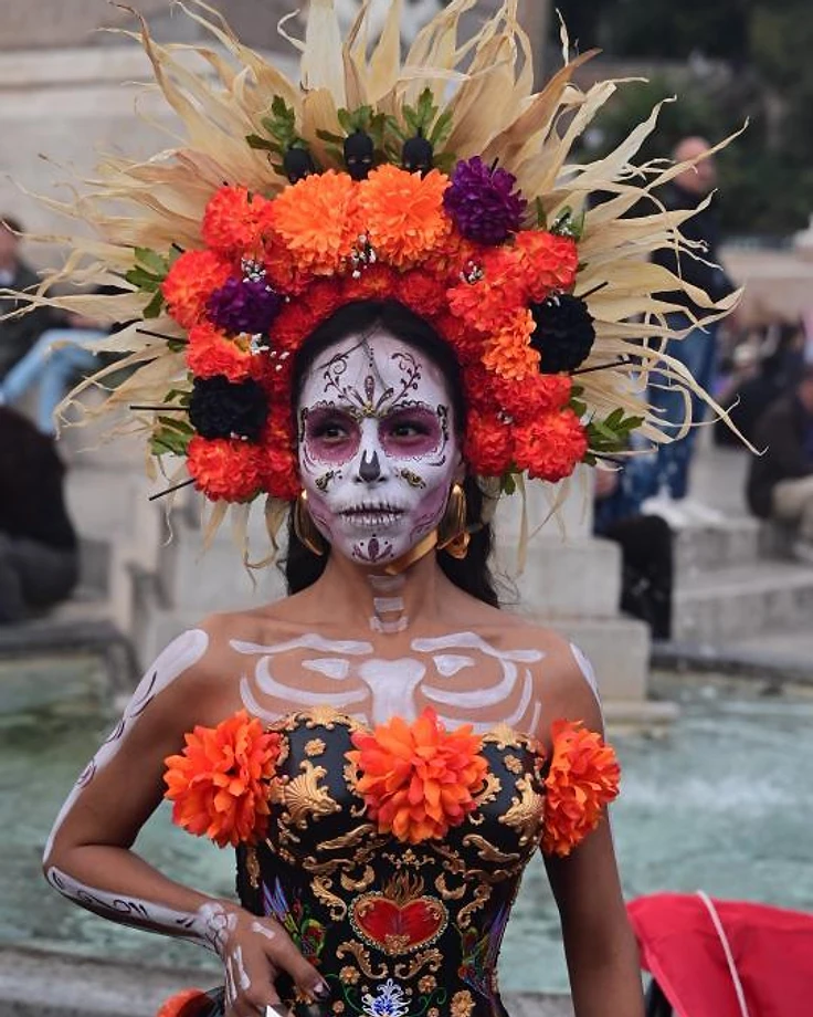 Donna con trucco da Catrina e corona di fiori di cempasúchil, in costume tradizionale per il Día de los Muertos.