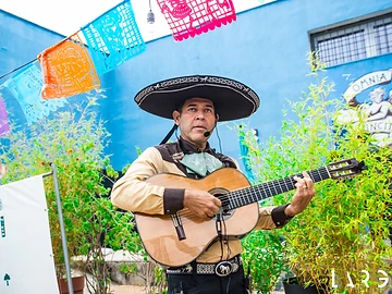 Musicista con sombrero e chitarra davanti a papel picado durante il Día de los Muertos Roma 2025.