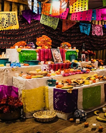Altare tradizionale dell'ofrenda con papel picado, fiori di cempasúchil e candele accese.