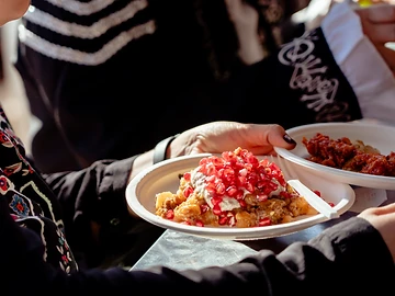 Piatti della cucina messicana tra le mani dei partecipanti durante il Día de los Muertos Roma 2023.