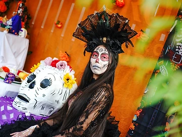 Partecipante con trucco da Catrina accanto a una calavera decorata durante il Día de los Muertos Roma 2024.