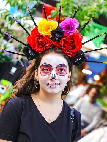 Partecipante con trucco da calavera e corona di fiori durante il Día de los Muertos Roma 2024.