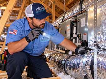 Adams & Sons technician inspecting indoor HVAC equipment in a Wilmington, NC attic during a heat pump service call