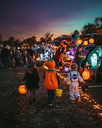 Kids in costumes walking toward glowing trunks