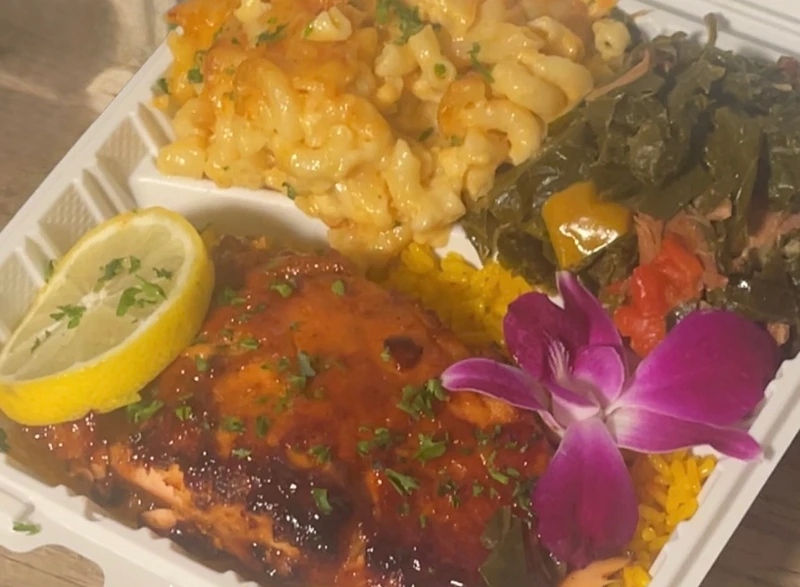 Meal prep container with mac and cheese, collard greens and glazed salmon over rice