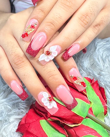 Square nails with nude base, red glitter French tips, 3D flowers, and gold butterfly charms
