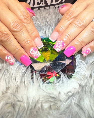 Square nails with hot pink polish and white floral art accents on a nude base