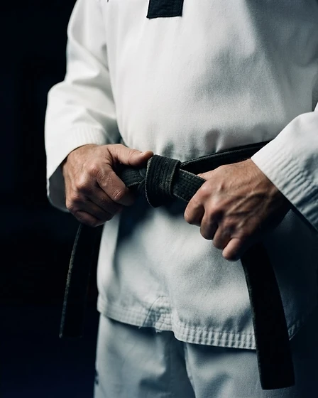 Martial artist tying a black belt