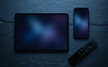 Television remote control beside a smart speaker on a dark side table