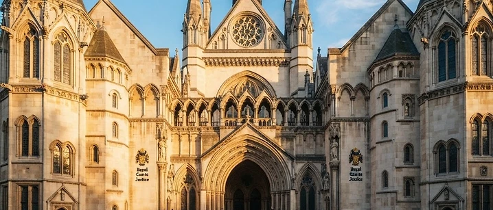 Historic stone courthouse facade in London lit by warm golden-hour sunlight