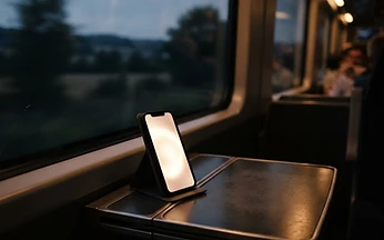 Smartphone glowing on a train tray table with dusky countryside blurred behind the window