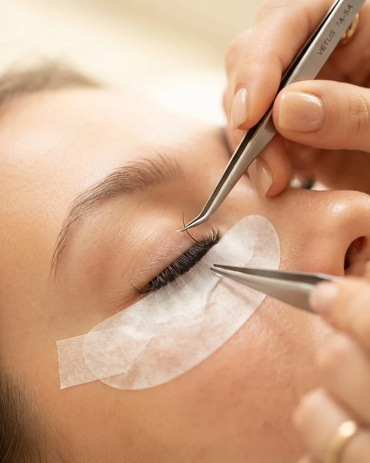 Close-up of a lash technician applying eyelash extensions