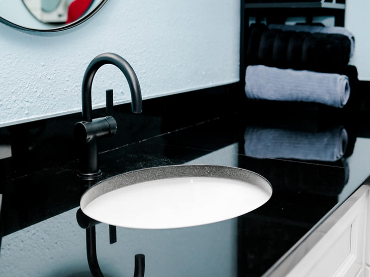 Bathroom vanity with black countertop, undermount sink and black faucet
