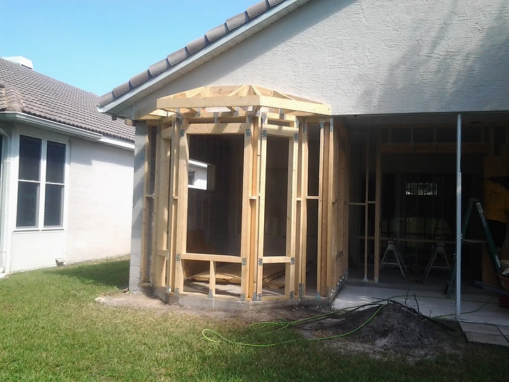 Hexagonal bay addition framing with roof trusses and hurricane straps on a stucco home by Home Res-Q