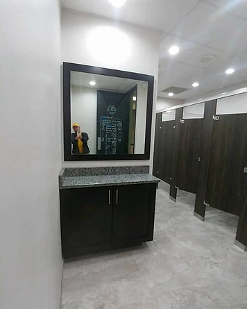 Commercial restroom vanity and wood-grain stall partitions after renovation