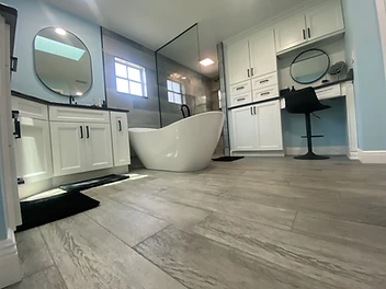 Completed coastal resort primary bathroom with freestanding tub, white shaker vanity and soft blue walls in New Port Richey