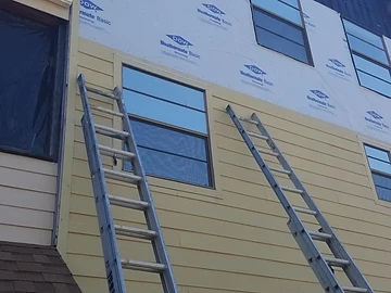 Siding installation in progress with siding material staged on an exterior wall