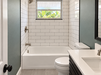 Wider view of a finished hall bathroom with subway tile and dark vanity by Home Res-Q