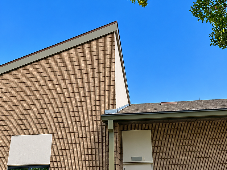 Tan ribbed siding and gray shingle roof on a commercial building exterior under a blue sky