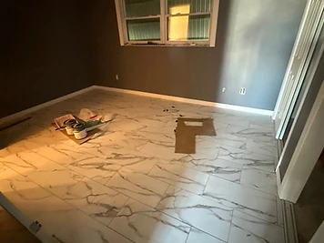 Completed plank flooring installation across a living area and kitchen transition