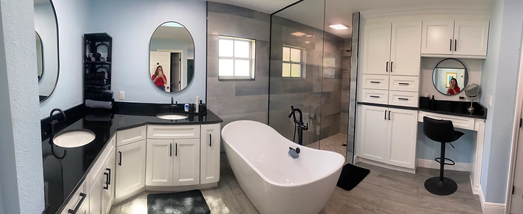 Completed coastal resort primary bathroom with freestanding tub, white shaker vanity and soft blue walls in New Port Richey