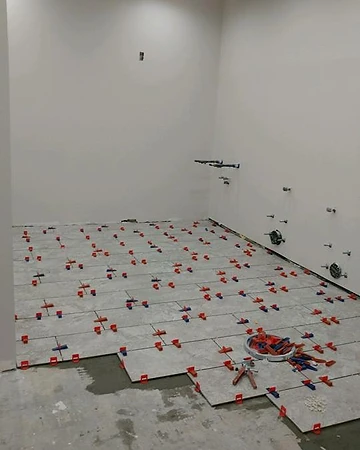 Tile flooring installation in progress with leveling clips and spacers