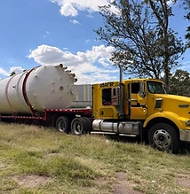 Tanque blanco sobre camión amarillo Kenworth