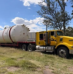 Tanque blanco sobre camión amarillo Kenworth