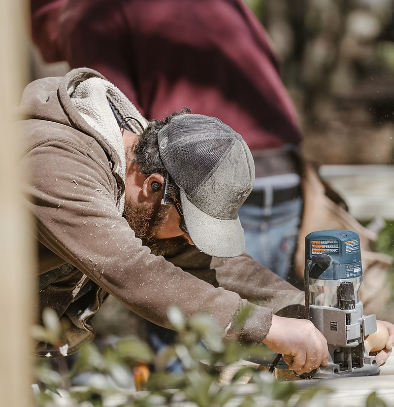 Handyman website design: a handyman holding a phone in front of a client's home
