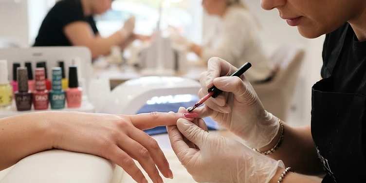 Nail technician applying gel polish in a bright nail salon