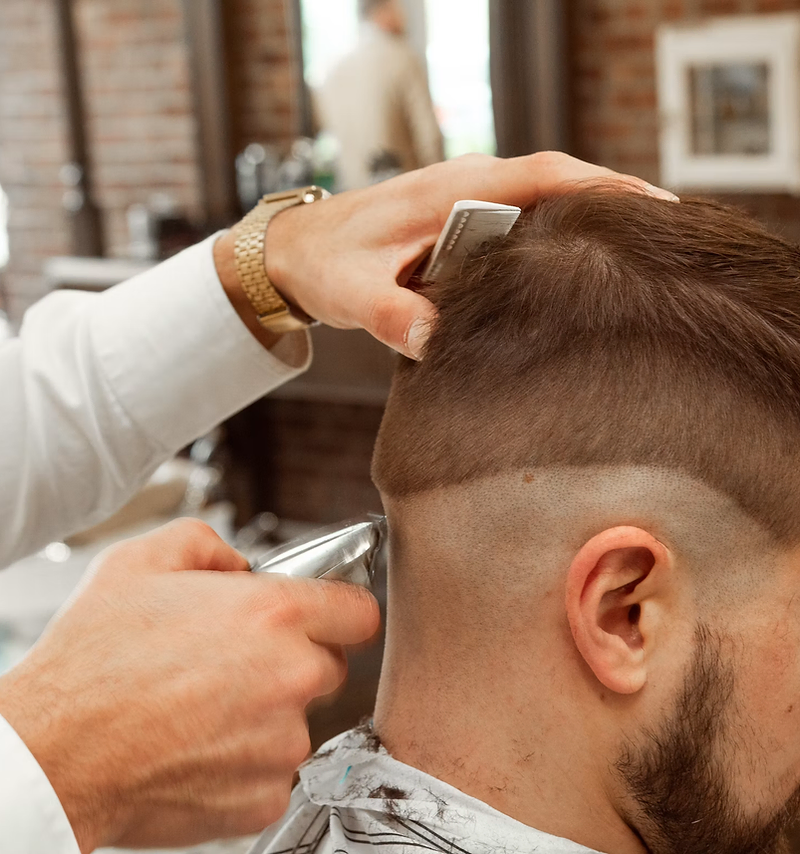 Barbershop website design: barber trimming a client's beard in a classic shop