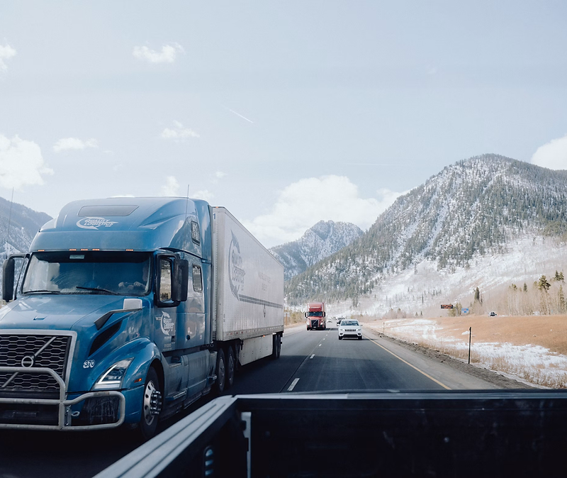 Semi truck driving on a highway at sunrise