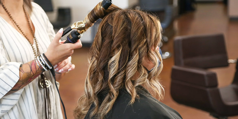 Hair stylist curling a client's hair in a salon