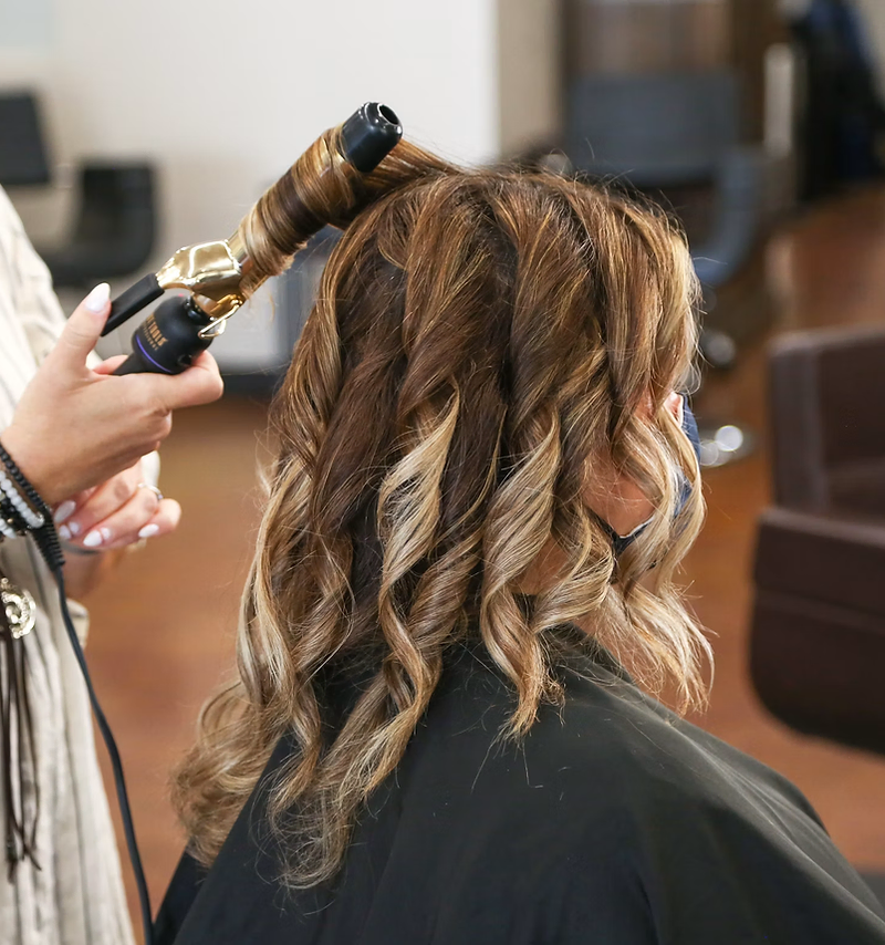 Salon website design: stylist curling a client's hair in a salon