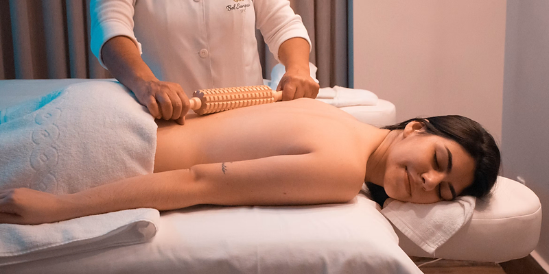 Massage therapist using a wooden roller on a client's back