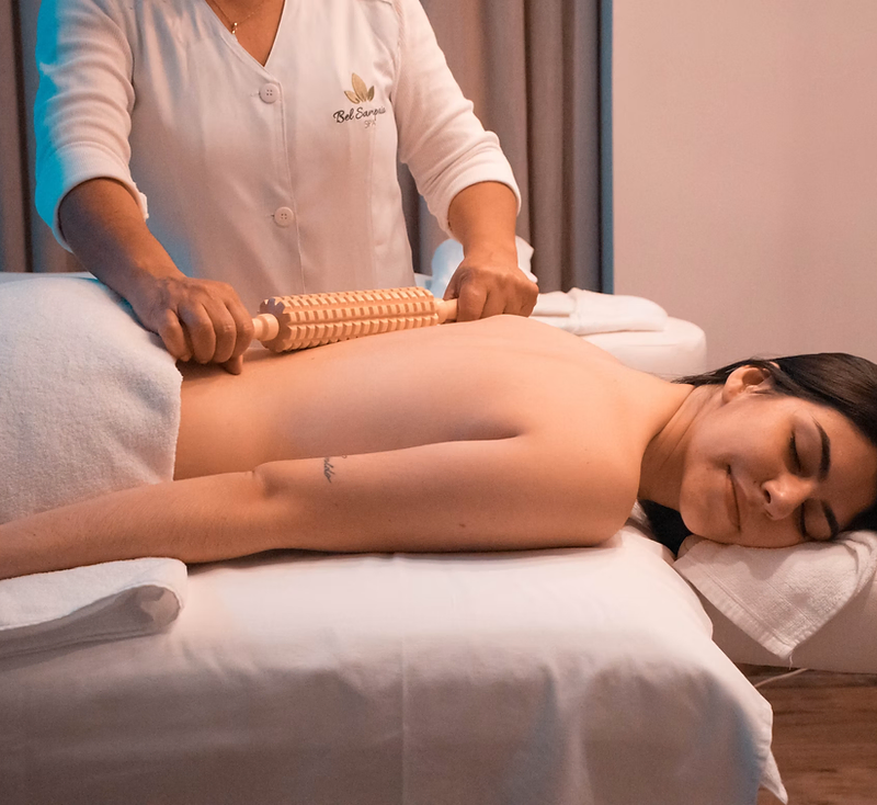 Massage therapist using a wooden roller on a client's back