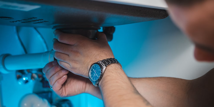 Plumber fixing pipes under a sink