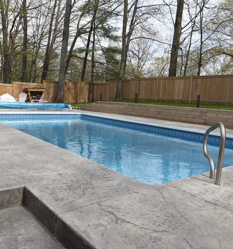 Pool company website design: clean backyard pool with stamped concrete deck