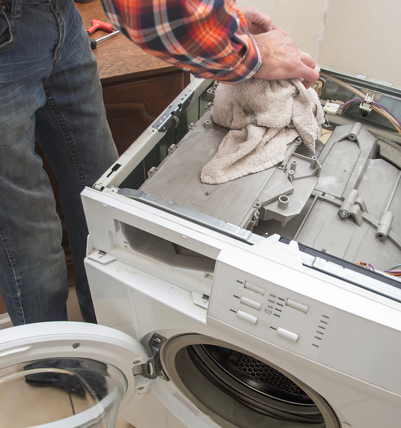 Appliance repair website design: technician repairing an open washing machine in a home