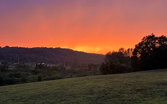 A vibrant sunset over the meadow and hills