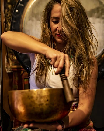 A practitioner playing a brass singing bowl before a gong
