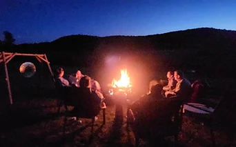 A campfire gathering under the night sky outside The Organ Barn