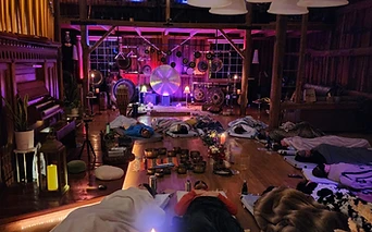 A sound bath gathering under magenta light inside the barn