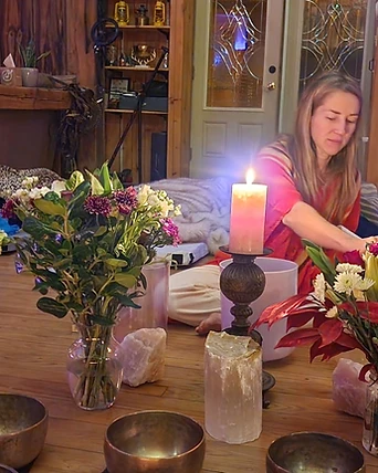 A practitioner at a crystal singing bowl by candlelight