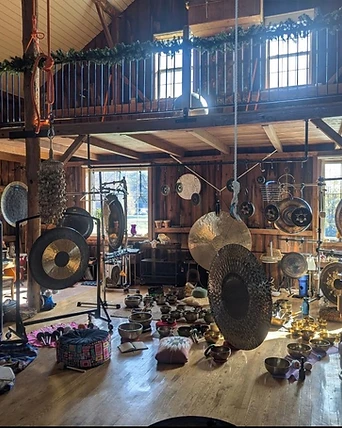 Singing bowls and gongs arranged on the barn floor in daylight