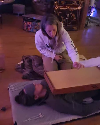 A practitioner working with a monochord over a resting participant
