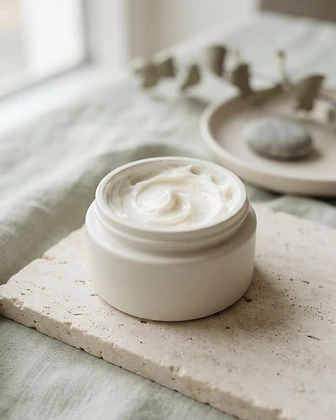 Open porcelain jar of Barrier Moisturizer showing a soft cream swirl on pale stone